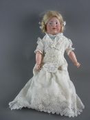 A KAMMER & REINHARDT BISQUE HEADED GIRL DOLL, fixed eyes looking to the right, white silk dress with