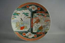 A JAPANESE IMARI WALL CHARGER having central panels depicting a seated lady, the other with a gilt