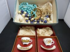 Box of costume jewellery and two boxed miniature cabinet cups and saucers