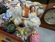 Staffs pottery Scottish figural group clock, a porcelain figure pin cushion and a Continental