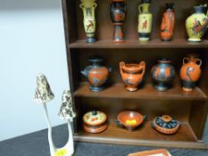 Miniature collection of 'The Treasures of Greece' vases on a wooden shelf and a porcelain