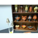 Miniature collection of 'The Treasures of Greece' vases on a wooden shelf and a porcelain