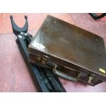 Vintage small leather suitcase and a surveyor's tripod stand