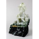 Guanyin, China um 1900. Sitzende Figur mit Fohund und Attributen aus hellgrüner Jade mit