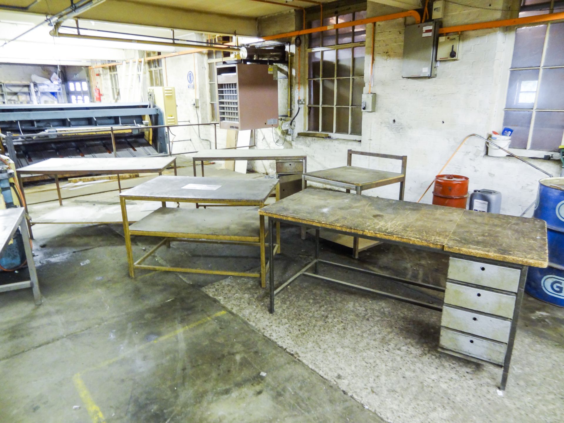 Five Assorted Workbenches, with welded steel tubular frameworks and chipboard tops, (part with