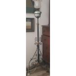 An Arts and Crafts Wrought Iron and brass adjustable oil standard lamp, with green painted reservoir