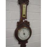 An aneroid barometer in carved oak frame and a circular framed barometer