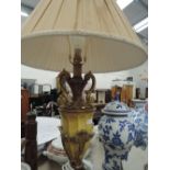 A table lamp with a tapered column base and gilt finish with shade