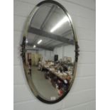 An oval wall mirror in metal frame