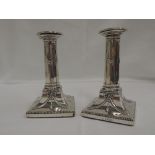 A pair of Victorian silver candlesticks having gadrooned decoration to sconces and bow and swag