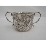 An Edwardian silver sugar bowl having moulded swan neck handles and repousse floral decoration,