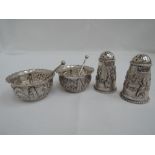 An Indian white metal 4 piece cruet set consisting of two pepperettes and two salts with spoons