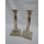 A pair of silver candlesticks of Corinthian column form having square stepped bases and beaded