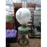 A brass oil lamp with ceramic well, etched glass shade and chimney