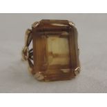 A ladies dress ring having a large citrine stone in a raised mount with moulded bow shoulders on a