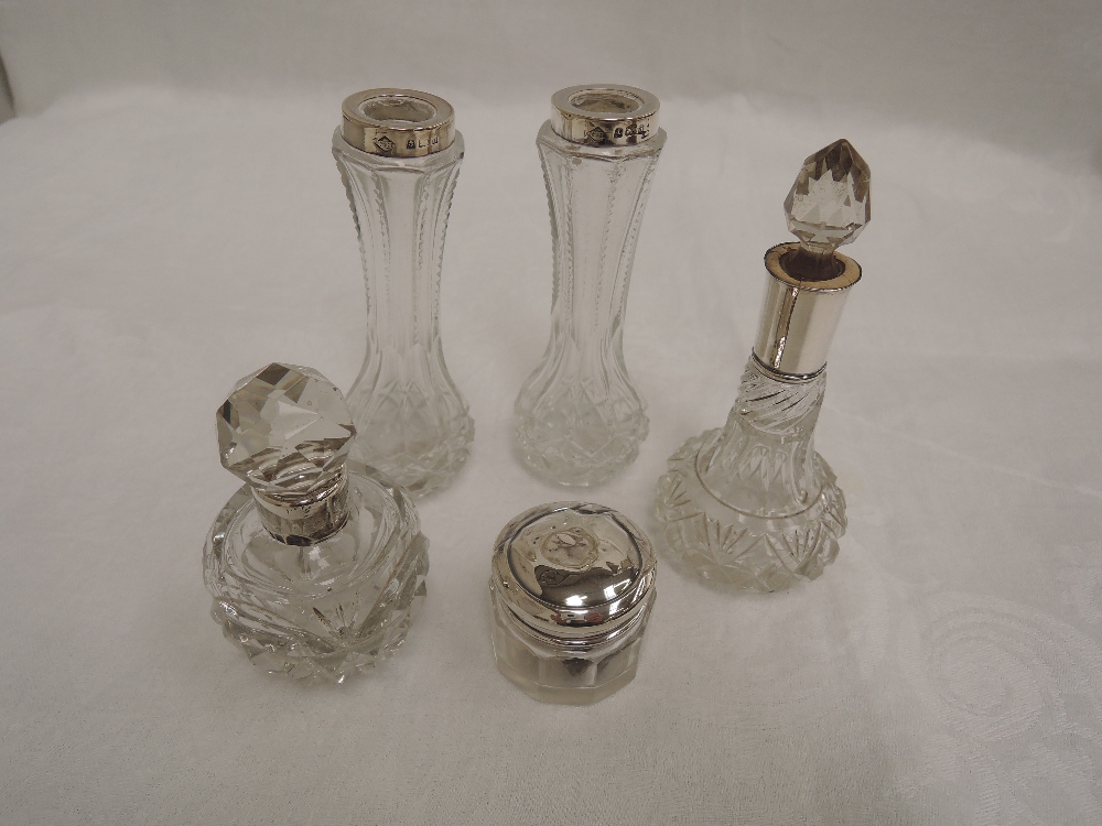 Five cut glass dressing table pots including perfume bottles, all having HM silver collars