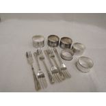 Six HM silver napkin rings of various designs and a set of six HM silver cake forks