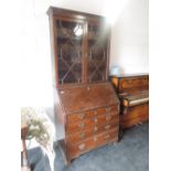 An early 19th century George III oak bureau bookcase having astral glaze top over slope front and