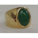 A yellow metal shaped band ring stamped 18K having an oval jade stone, approx 3ct stone