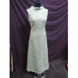 A lady's 1960's sleeveless long evening dress in gold lame on apple green ground having high neck