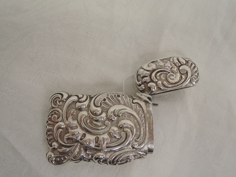 An American silver vesta case of long form having extensive repousse scroll decoration, stamped