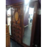 A late Victorian mahogany and walnut wardrobe having central oval panelled cupboard on drawers,