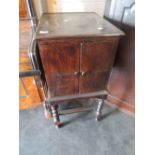 A 1920's oak record cabinet having cupboard slat top on twist legs