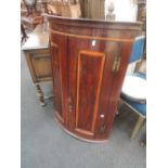 An early 19th century George III mahogany bow front corner cupboard having crossband decoration