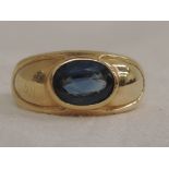 A yellow metal shaped band ring stamped 18K having a powder blue sapphire stone to moulded