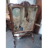 A mid Victorian mahogany firescreen having scroll frame with Berlin woolwork tapestry inset