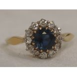 A lady's dress ring having a sapphire and diamond cluster on a yellow metal loop stamped 18