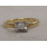 A lady's dress ring having an emerald cut diamond solitaire, approx .45ct in a raised four claw