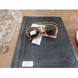 A pair of Christian Dior sunglasses, one pound note and vintage postcard album