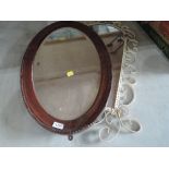 An oval wood framed mirror and painted metal framed arch mirror