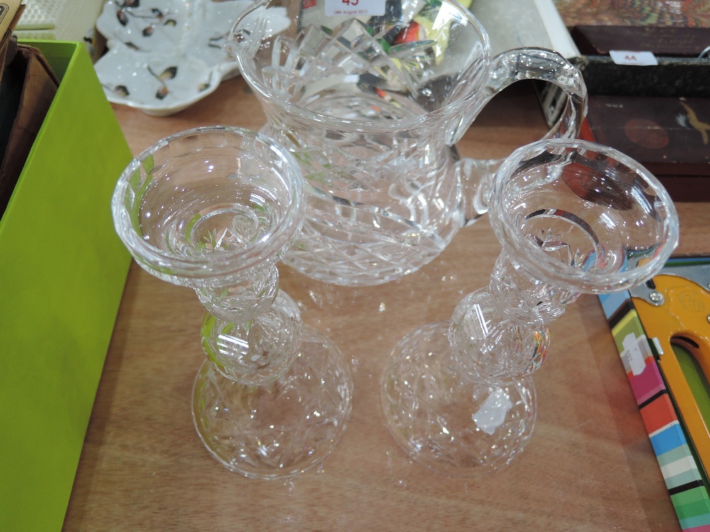 A pair of cut glass candlesticks and a cut glass water jug