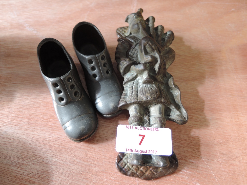 A vintage cast door knocker modelled as a piper and a pair of metal work ornamental shoes