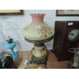 A cast framed table lamp with hand painted glass shade and milk glass chimney