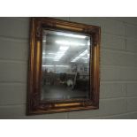 A gilt and plaster effect mirror with bevel edge glass