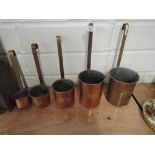 A selection of vintage copper measuring jugs with long brass stem handles and name badge