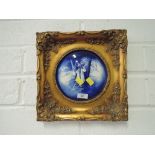 A pair of antique gilt and plaster framed ceramic tiles in a delftware style depicting winter and