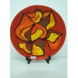 A Poole pottery charger/plaque of stylised 1960's design, on red ground