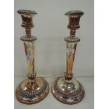 A pair of Sheffield plate candle sticks having tapered columns to circular weighted bases with