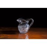 A 19TH CENTURY CUT GLASS JUG, of baluster form with diamond fold banding, and c-scroll handle.