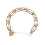 A GOLD BRACELET The gold gate-link bracelet with a heart-shaped padlock clasp and security chain,