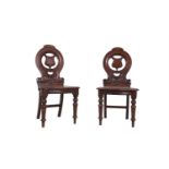 A PAIR OF VICTORIAN MAHOGANY HALL CHAIRS, the circular open backs with vacant shield, the shoe