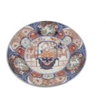 A LARGE JAPANESE PORCELAIN IMARI CHARGER the central reserve decorated with a still life within a