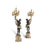 A PAIR OF EBONISED, PAINTED AND GILDED BLACKAMOOR TORCHERES, the standing figures, raised on