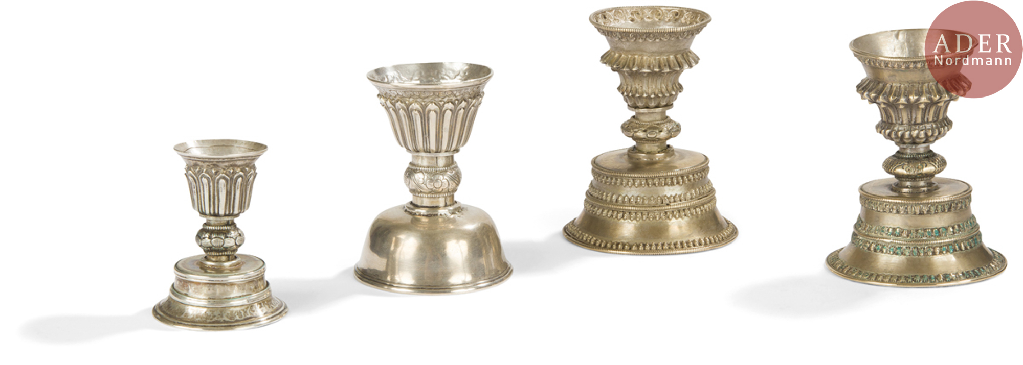 TIBET - XIXe siècle Ensemble de quatre lampes à beurre en argent reposant sur des piédouches à décor