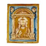 Placa de cerámica esmaltada en azul y reflejo metálico, con Cristo bendiciendo en relieve, bajo un
