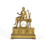 Reloj de sobremesa de bronce dorado con figura sobre plinto, esfera esmaltada con numeración romana.